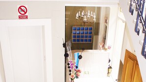 A staircase with a metal railing leading to a room with a chandelier and a vase of flowers. - Hotel Rosal (Oviedo)