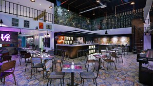 A spacious restaurant with a high ceiling, multiple seating areas, and a bar. - favehotel Kuta Kartika Plaza (Kuta)