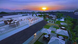 A rooftop terrace with outdoor seating and a view of the sunset over the ocean.