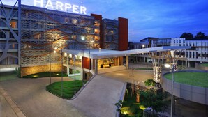 Un hotel moderno con un'insegna ben visibile 'HARPER', una zona esterna coperta e un cortile curato.