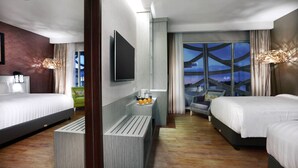 Una moderna camera d'albergo con due letti, una TV a schermo piatto, un tavolino con arance e vista sulla Torre Eiffel.