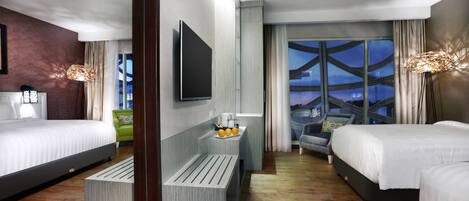 A modern hotel room with two beds, a flat-screen TV, a small table with oranges, and a view of the Eiffel Tower.