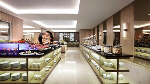 Un buffet moderno in un hotel, con diverse postazioni di cibo, banchi di servizio ordinati e un ambiente pulito e ben illuminato.