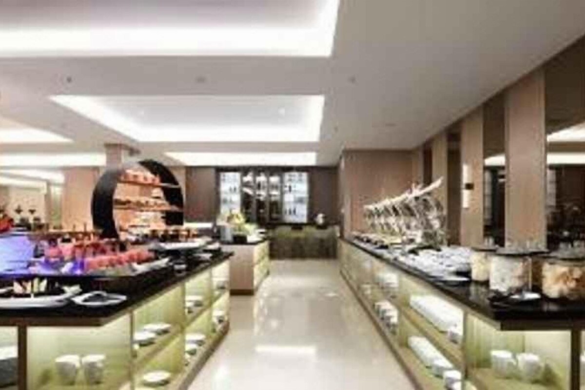 Um hall de hotel moderno com um balcão de recepção extenso, vitrines de vidro e uma área de estar central.