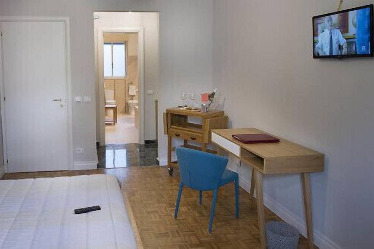 Une chambre à coucher avec un lit, un bureau, une chaise et un téléviseur fixé au mur.
