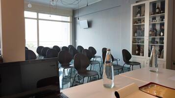 Een vergaderruimte met een lange tafel, meerdere stoelen, een waterfles en een whiteboard.