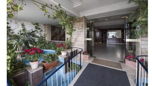A hotel lobby with a reception desk, potted plants, and a staircase. - Ciauru Design B&B (Messina)