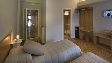 Una camera da letto con un letto, una scrivania, una sedia, una televisione e un cabina armadio.