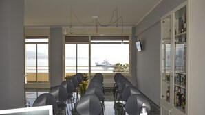 A conference room with rows of chairs facing a large window overlooking a body of water. - Ciauru Design B&B (Messina)
