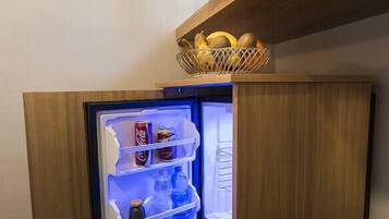 A refrigerator with a basket of bananas on top, containing beverages and snacks.