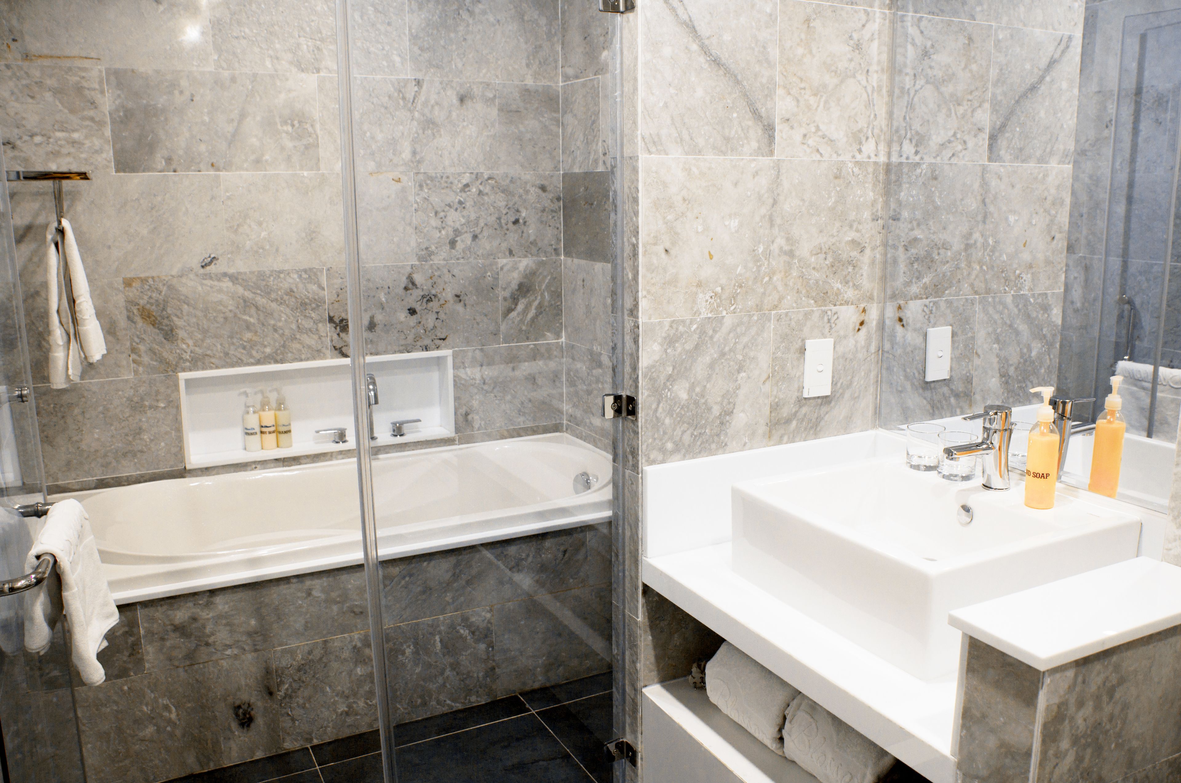 A modern bathroom with a glass-enclosed shower, a standalone bathtub, and a large white sink with a mirror.
