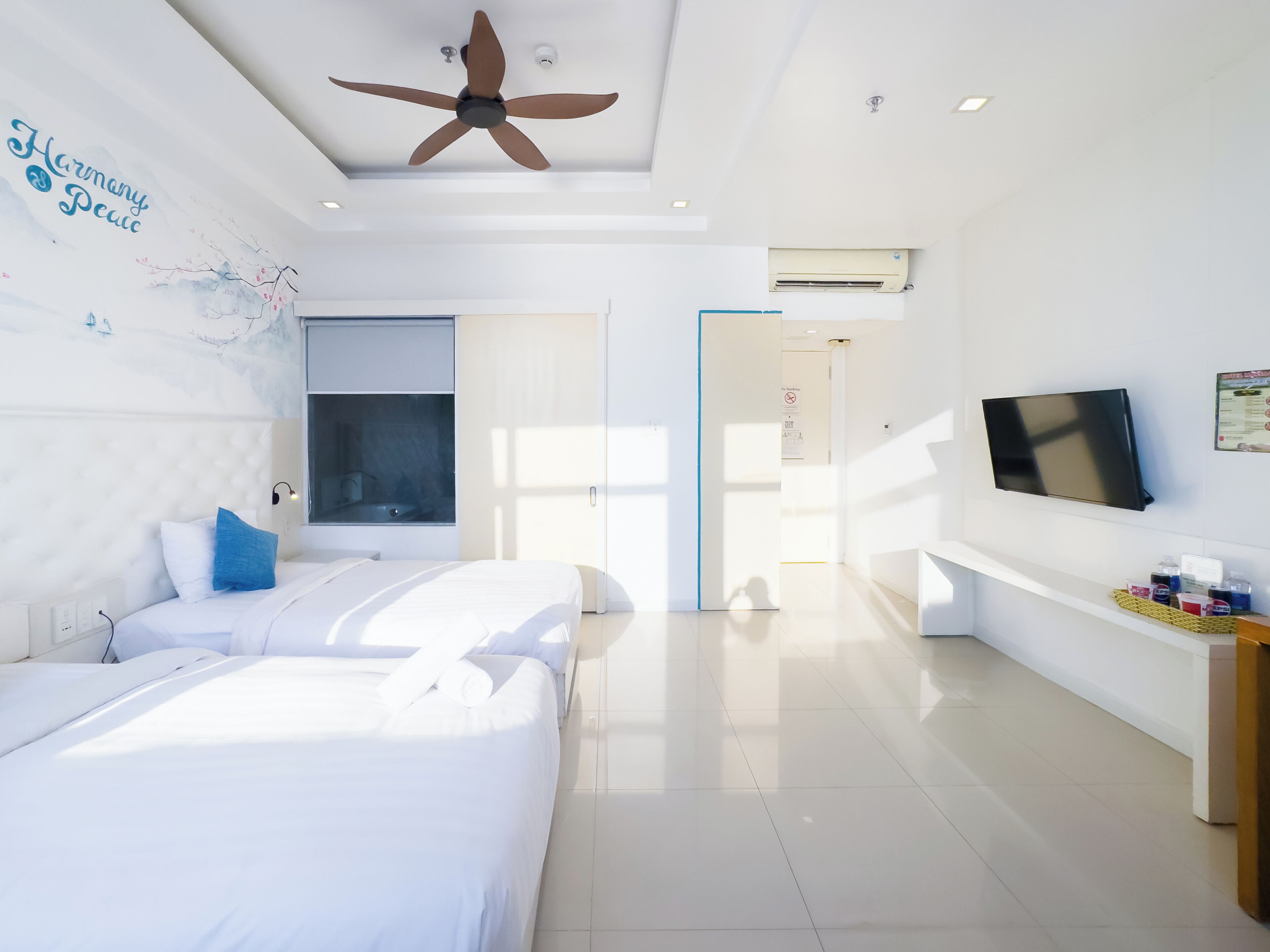 Una habitación de hotel moderna con cama, ventilador de techo, televisor y ventana.