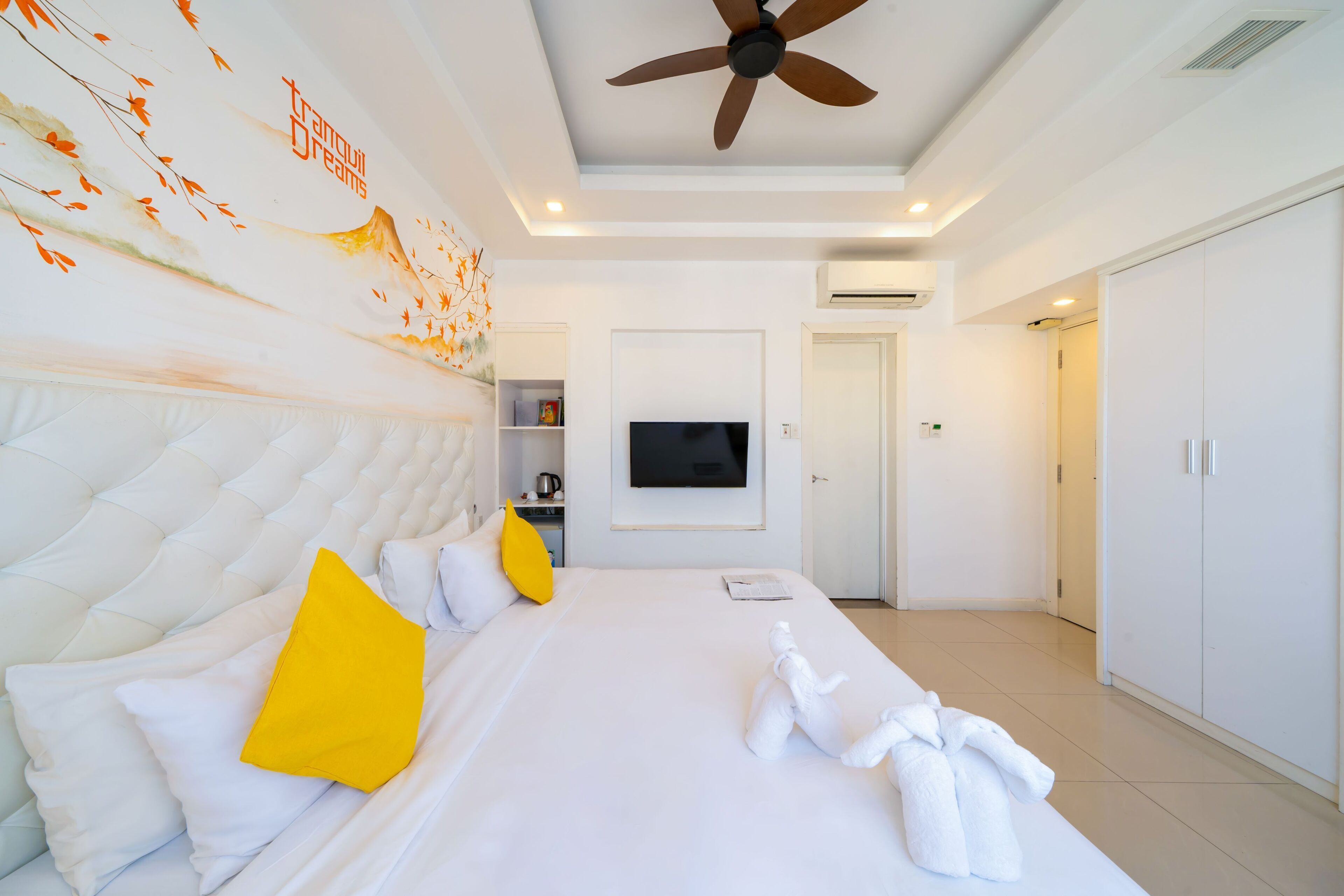 Une chambre d’hôtel avec un grand lit, un ventilateur de plafond, un téléviseur à écran plat et une armoire.