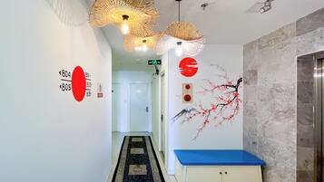 A hotel hallway with a blue bench, a wall with a red circle and a red moon, and a patterned carpet.