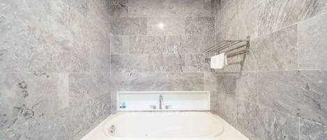A modern bathroom with a freestanding bathtub, marble walls, and a towel rack.