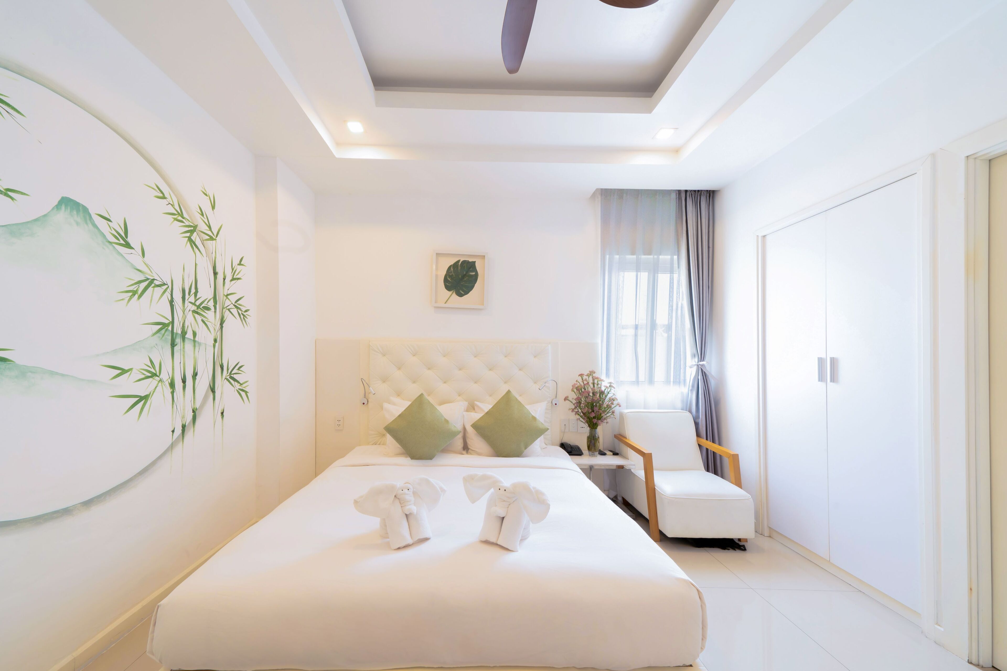 A modern hotel room with a large bed, a tufted headboard, a small desk, and a chair.