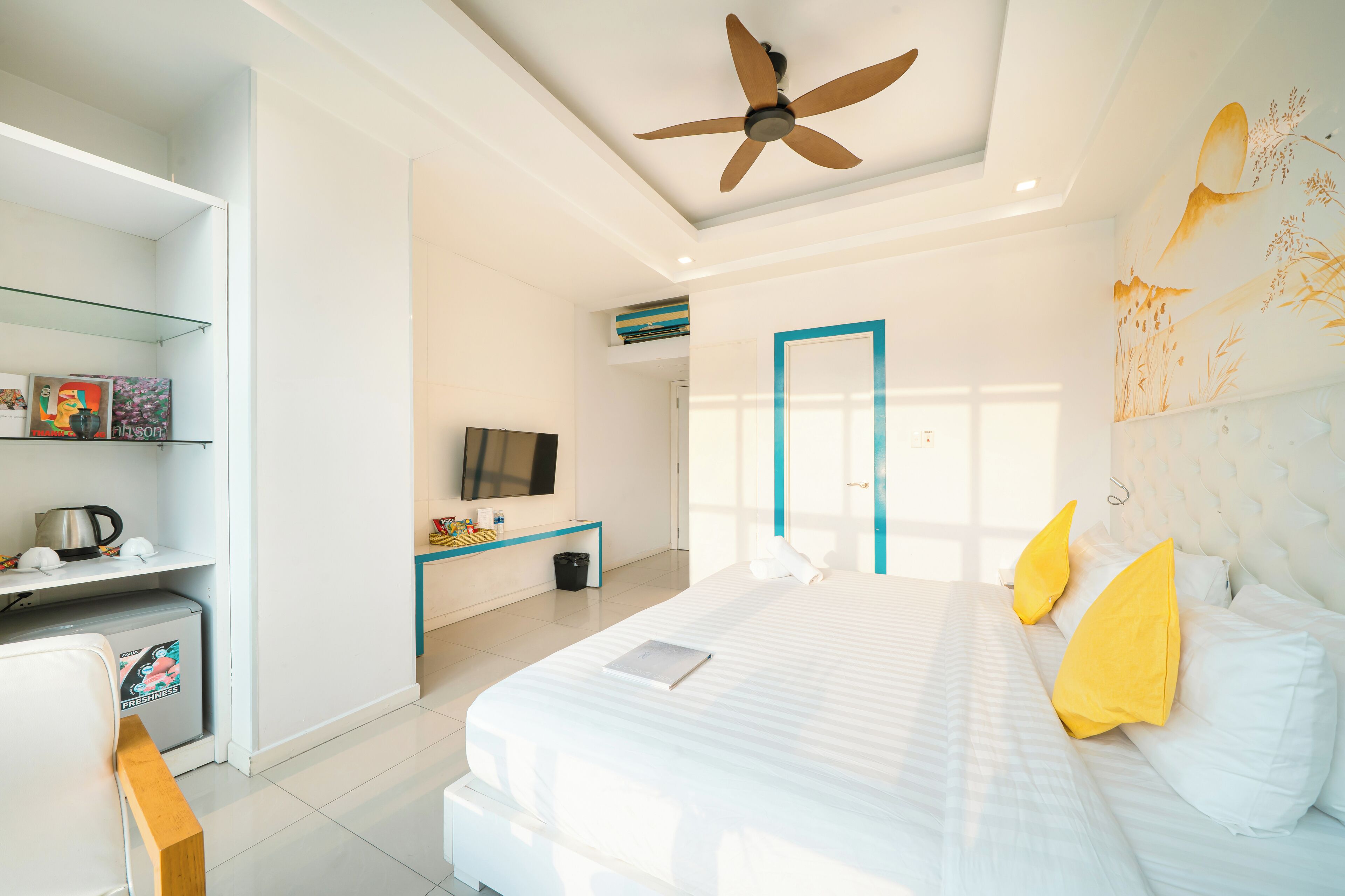 Una habitación de hotel con cama, escritorio, televisor y ventilador de techo.
