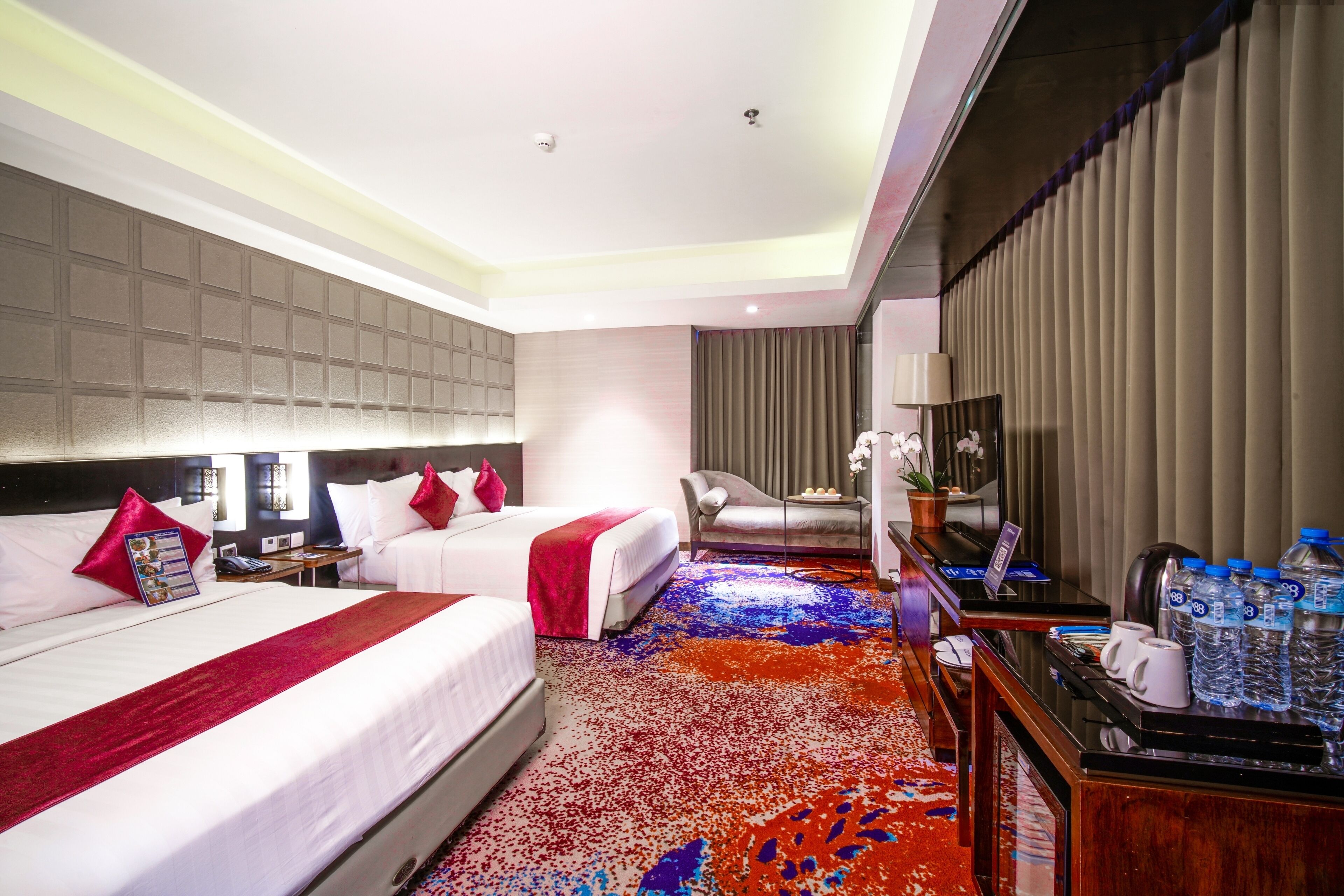 A hotel room with two beds, a desk, a chair, a TV, and a water dispenser.