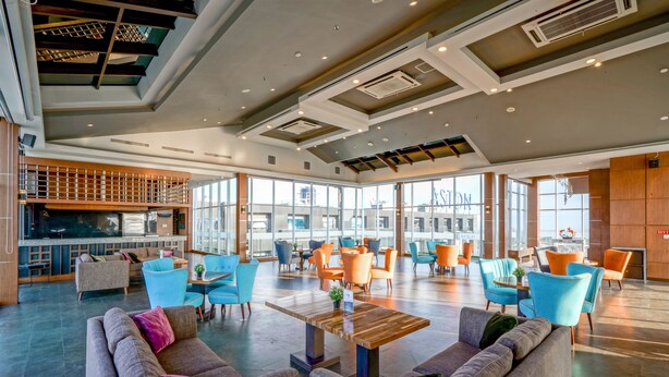 A spacious lobby with modern furniture, large windows, and a high ceiling with exposed beams. - Aston Pasteur (Bandung)