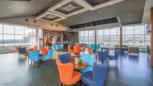 A spacious indoor area with high ceilings, large windows, and a variety of seating arrangements including tables and chairs. - Aston Pasteur (Bandung)
