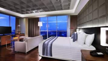 Una habitación de hotel moderna con una cama grande, un sofá, un televisor y vistas a la ciudad.