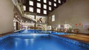 An indoor swimming pool with a clear view of the surrounding area, including a staircase and seating area. - Aston Pasteur (Bandung)