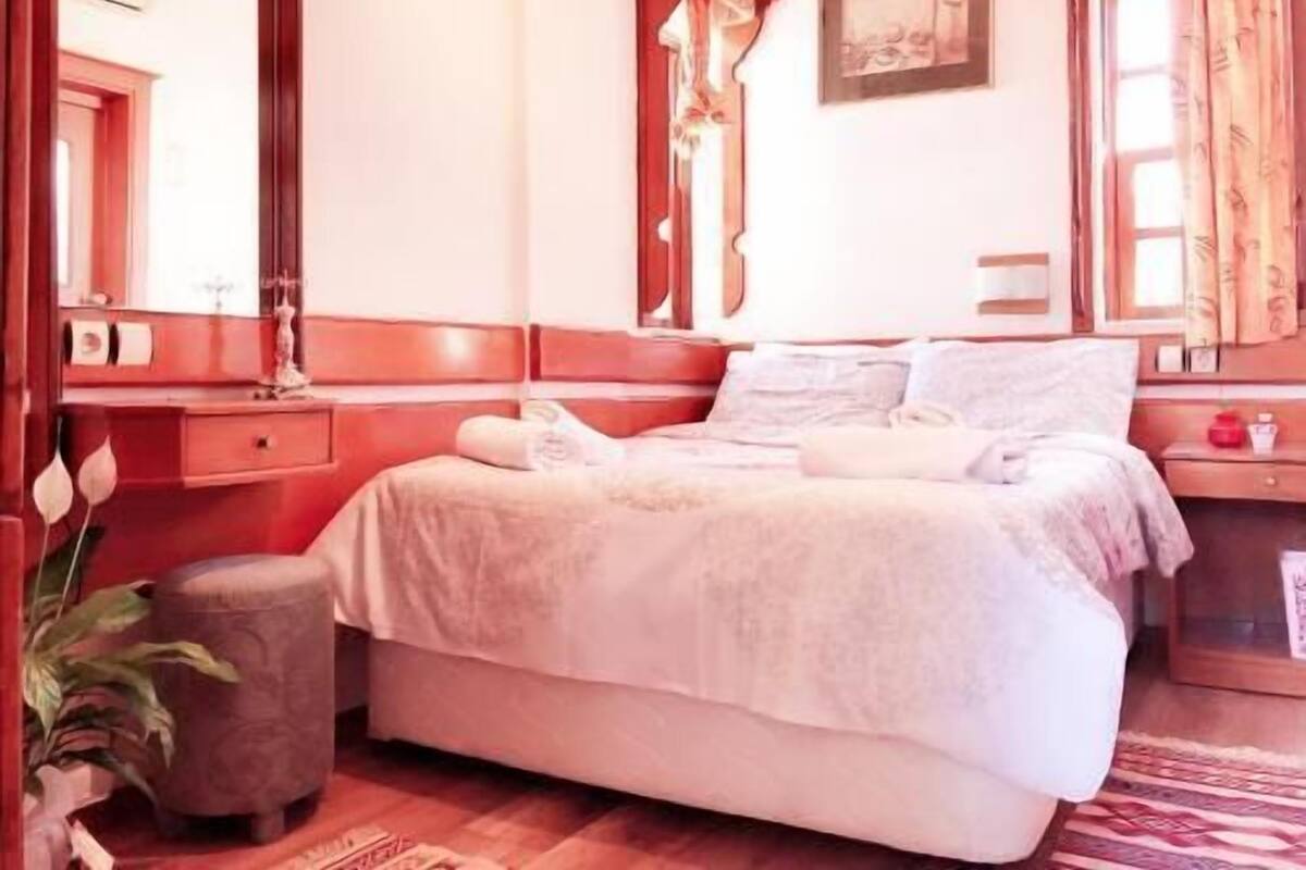 Una habitación de hotel con cama, mesita de noche, lámpara y espejo.