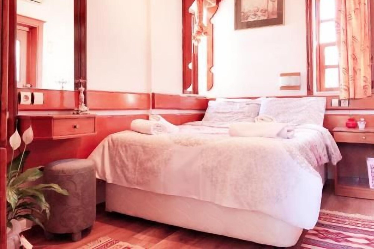 Une chambre d’hôtel avec un lit, une table de chevet, une lampe et un miroir.