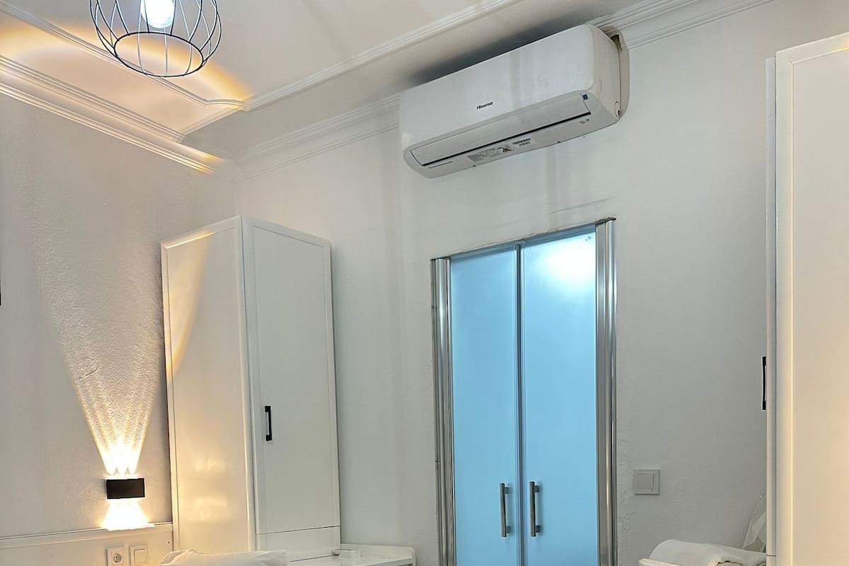 Habitación de hotel con cama, mesita de noche, armario y aire acondicionado.