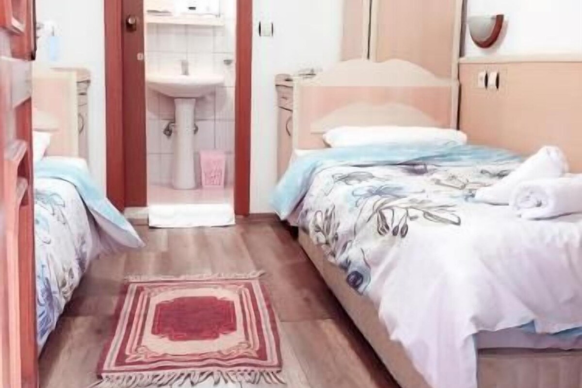 Une chambre à coucher avec un lit, une armoire, une salle de bain visible à travers une porte ouverte et un plancher en bois.