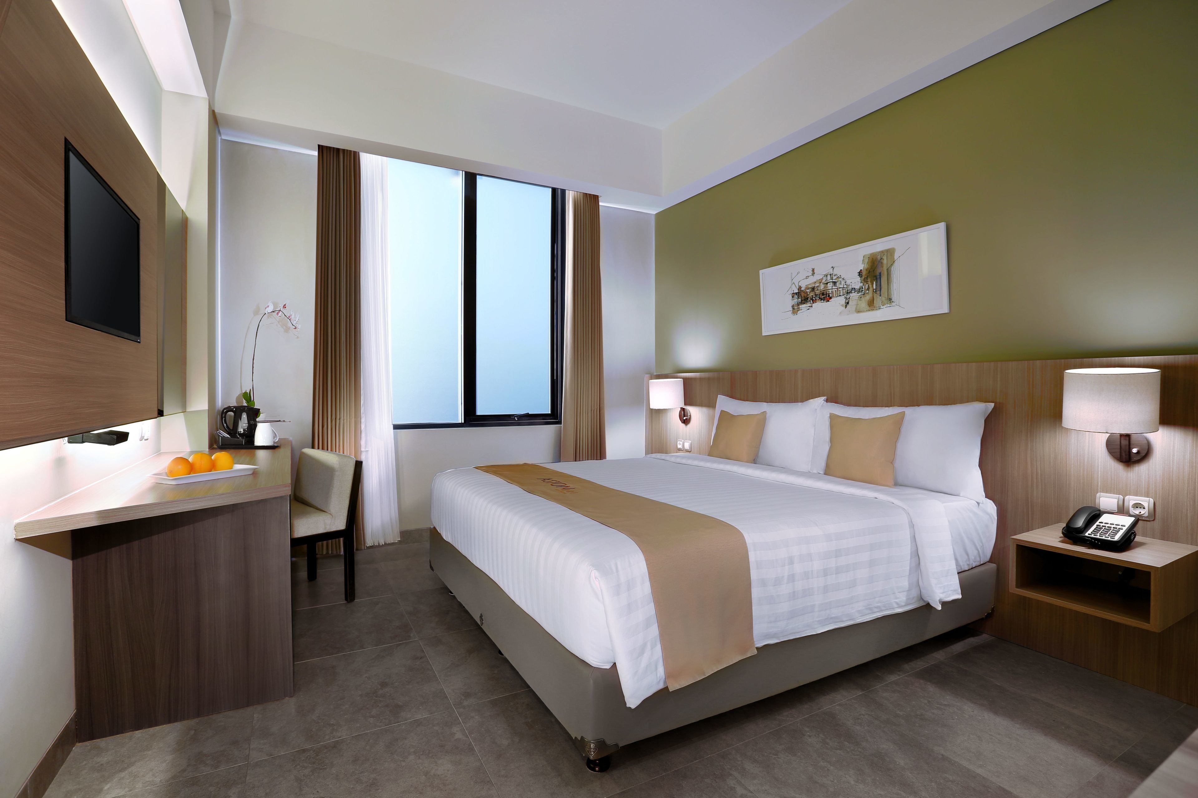 Una habitación de hotel con cama, mesitas de noche, escritorio, silla y televisor.
