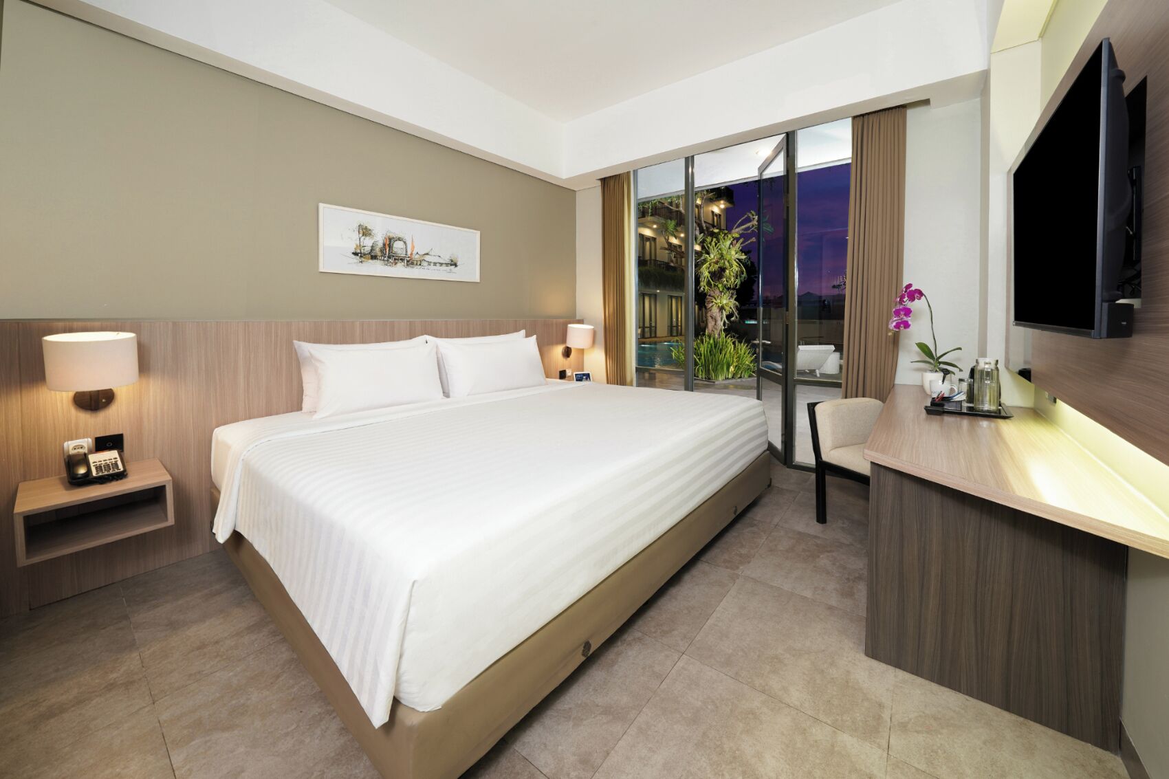 Une chambre d’hôtel dotée d’un grand lit, de tables de chevet avec des lampes, d’un téléviseur à écran plat, d’un petit bureau avec une chaise et d’une porte-fenêtre coulissante donnant sur un balcon avec vue sur le ciel nocturne.