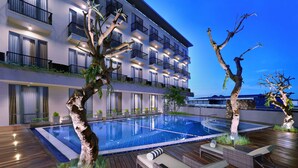 A modern hotel with a large outdoor swimming pool, wooden deck, and lounge area. - Aston Inn Mataram (Mataram)