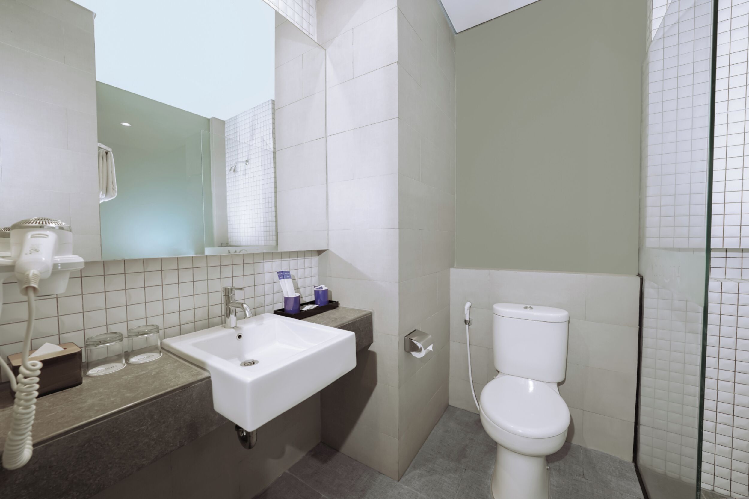 A bathroom with a white sink, mirror, and toilet.