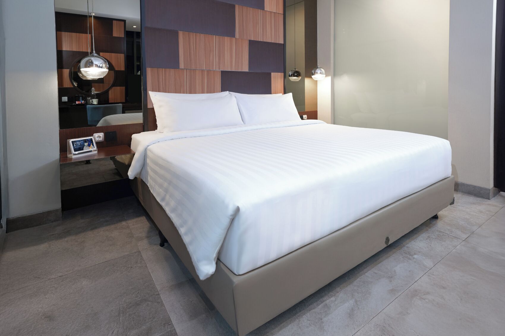 Une chambre d’hôtel moderne avec un grand lit, un bureau avec un ordinateur portable et un miroir.