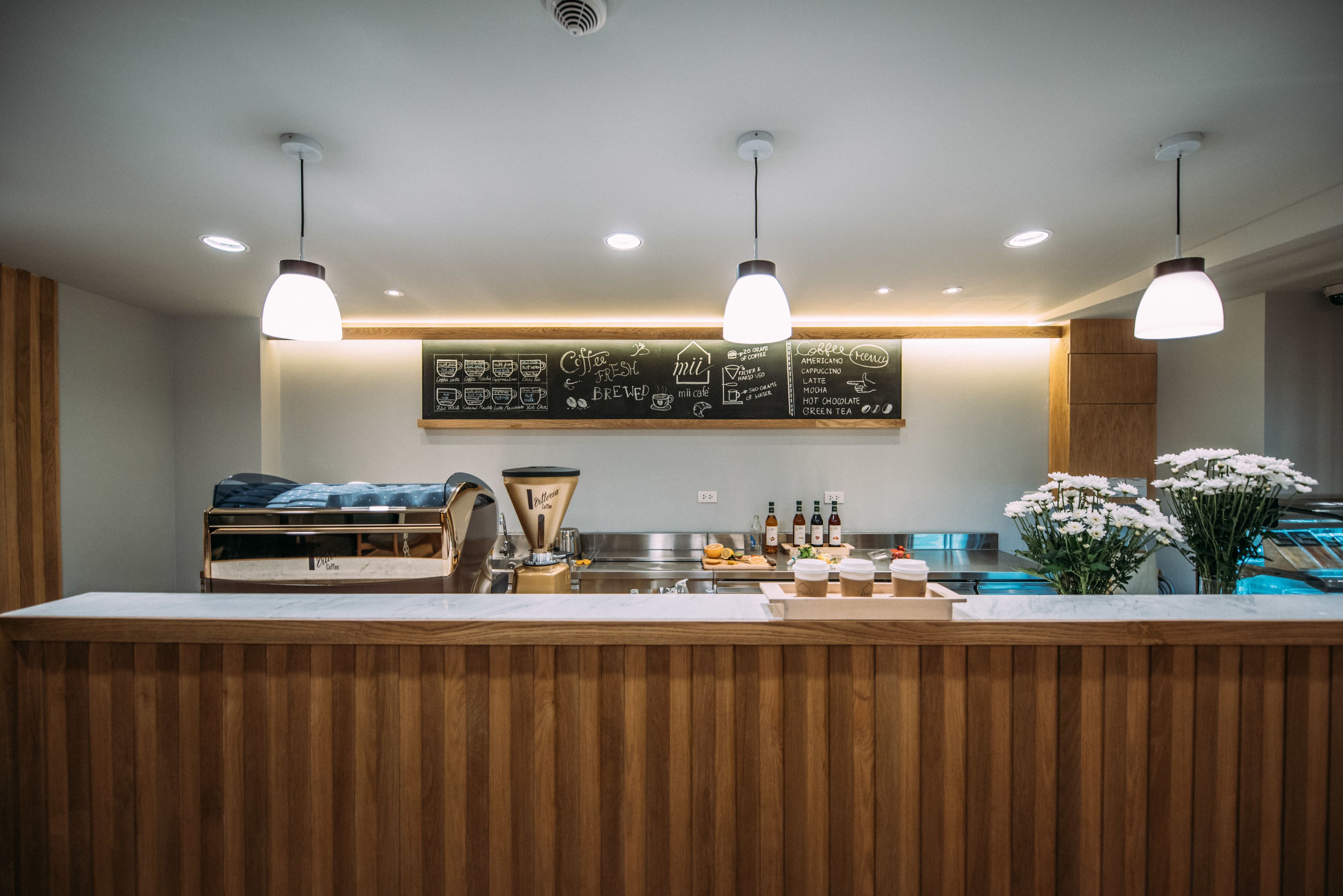A modern coffee shop interior with a wooden counter, espresso machine, and menu board.