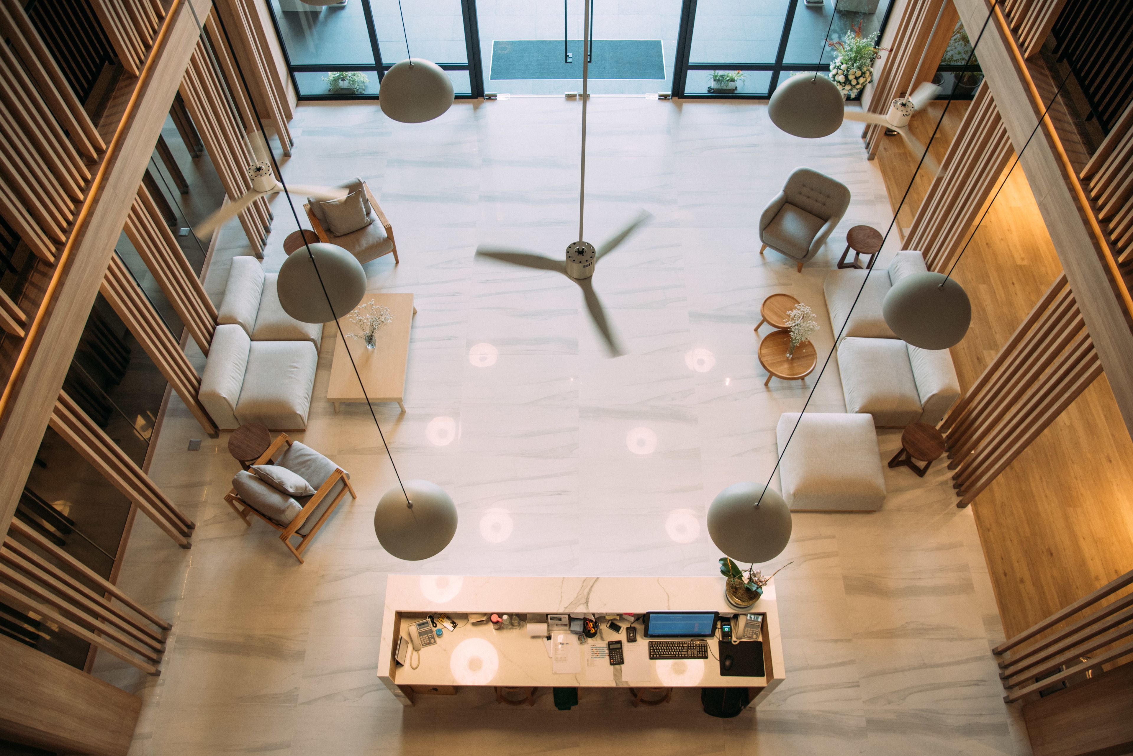 A spacious lobby with a central seating area, a reception desk, and a ceiling fan.