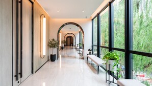 Un pasillo moderno de hotel con piso pulido, ventanas amplias y plantas en macetas.