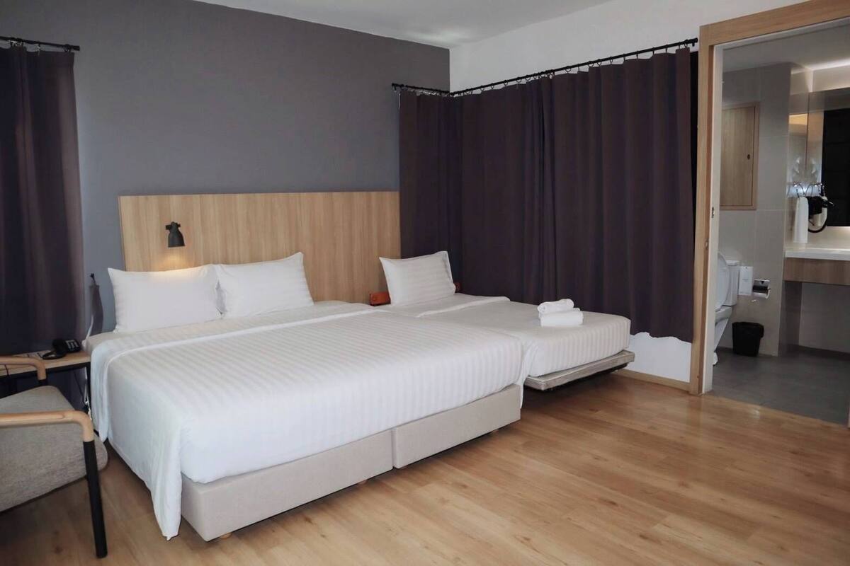 A hotel room with a large bed, a bedside table, a chair, and a bathroom visible through an open door.
