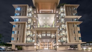 Un hotel de varios pisos con entrada central, balcones y un diseño arquitectónico moderno.