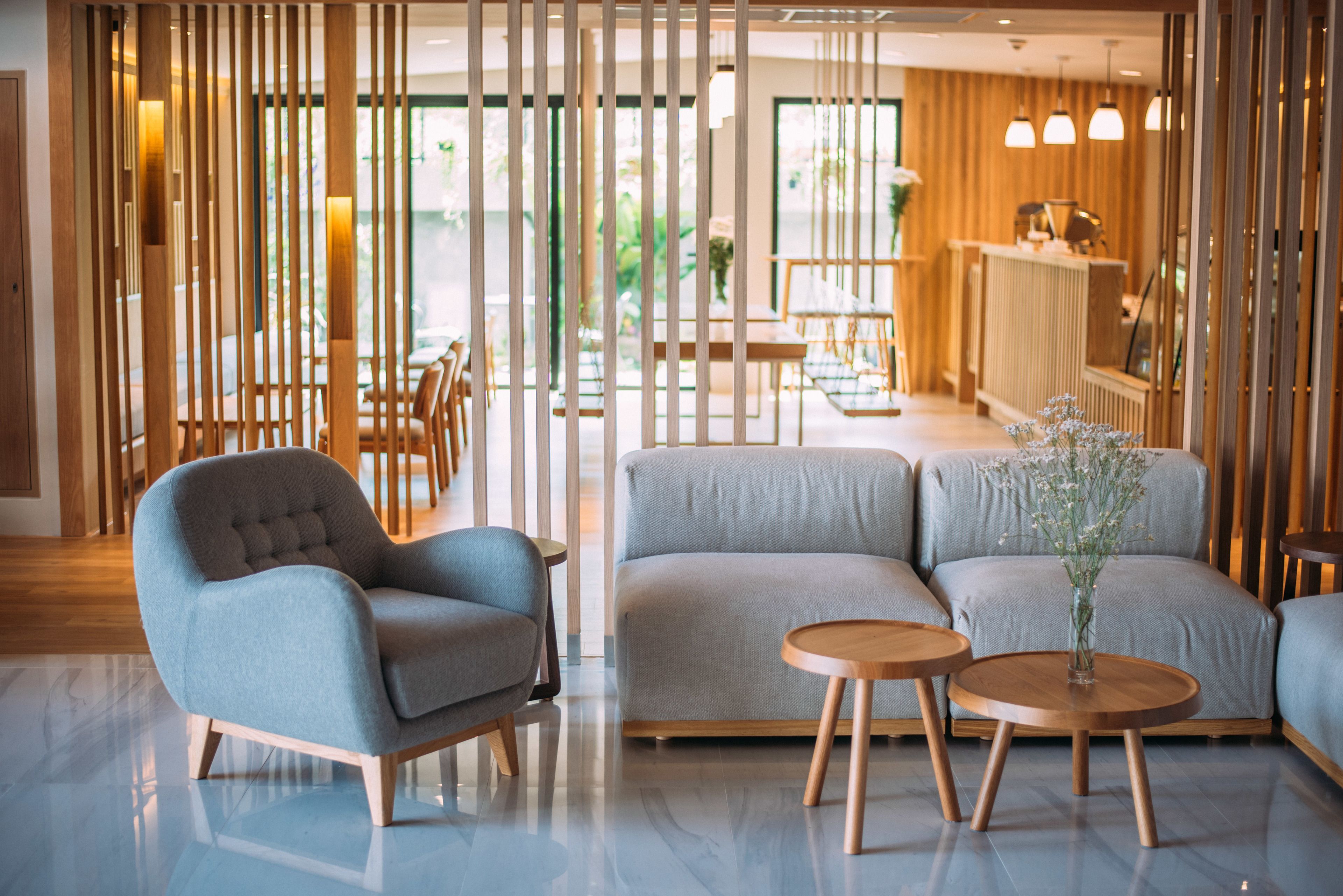 Un interior moderno con un sofá modular, un sillón capitoné y una mesa redonda de madera.