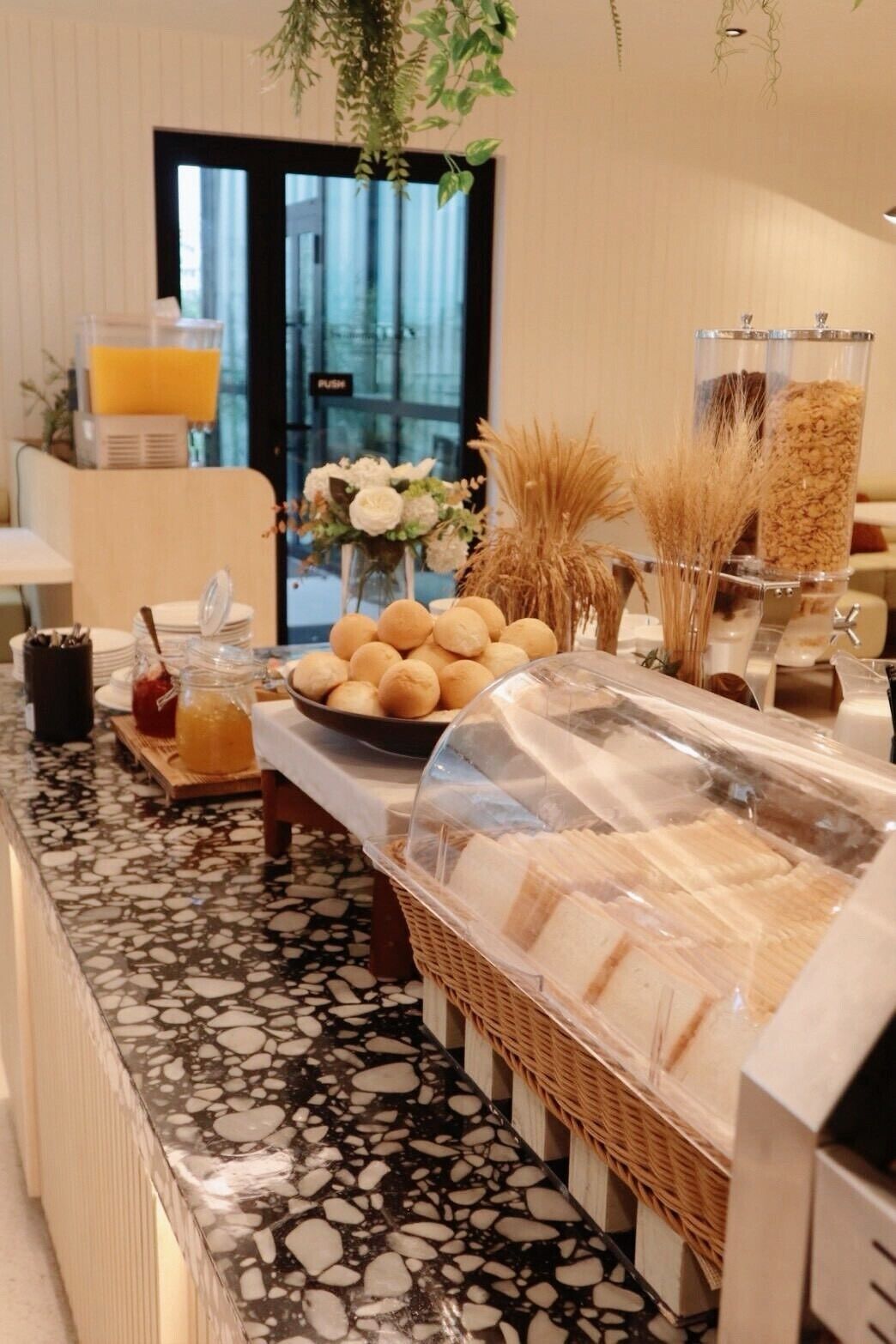 A buffet setup with bread, pastries, and beverages.