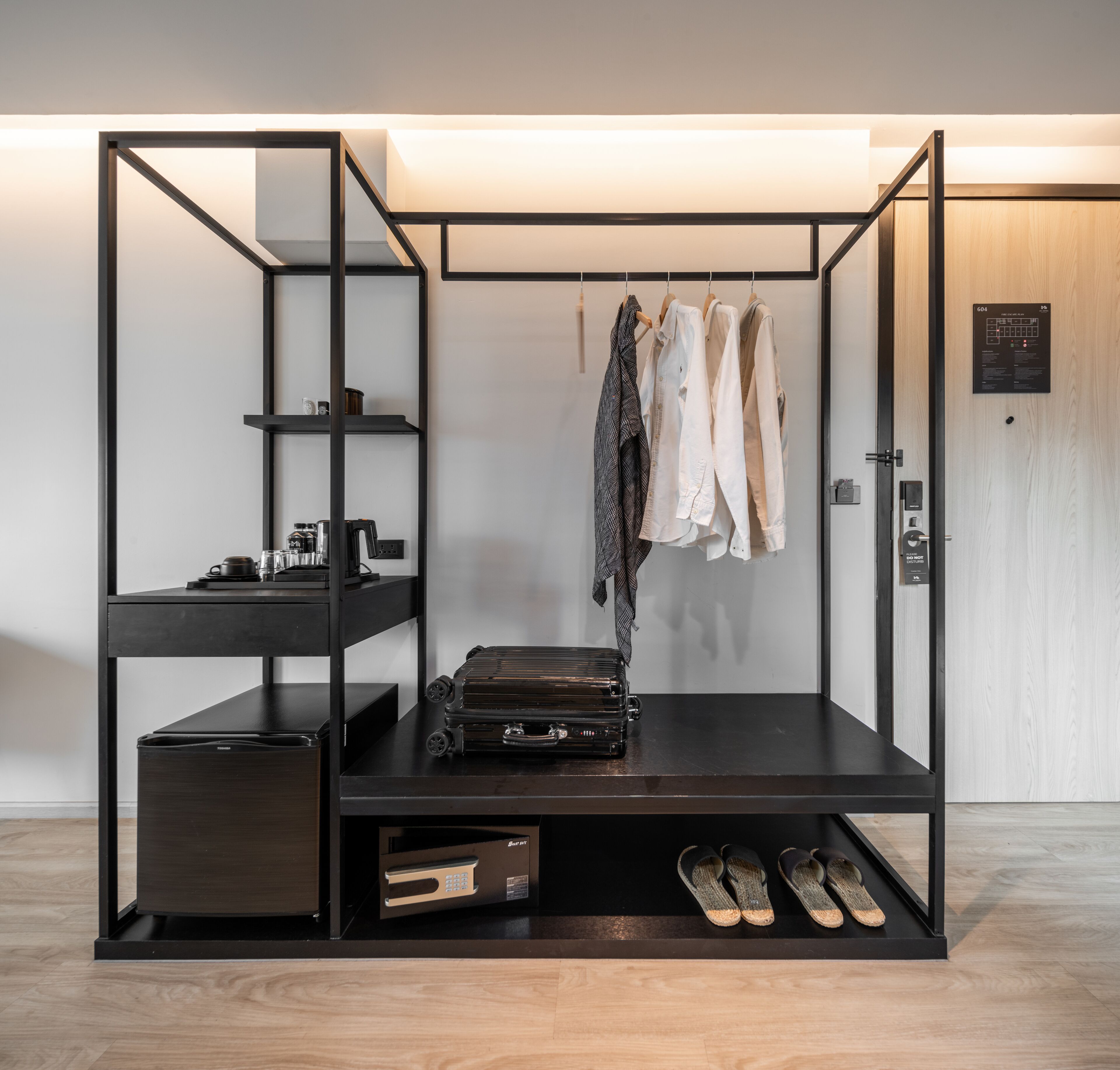 Une pièce compacte et moderne, dotée d’une armoire intégrée, d’un petit coin cuisine et d’un espace salon.
