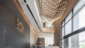 Un lobby espacioso de diseño moderno, con una zona de estar, una escalera y un gran ventanal con vistas al exterior.