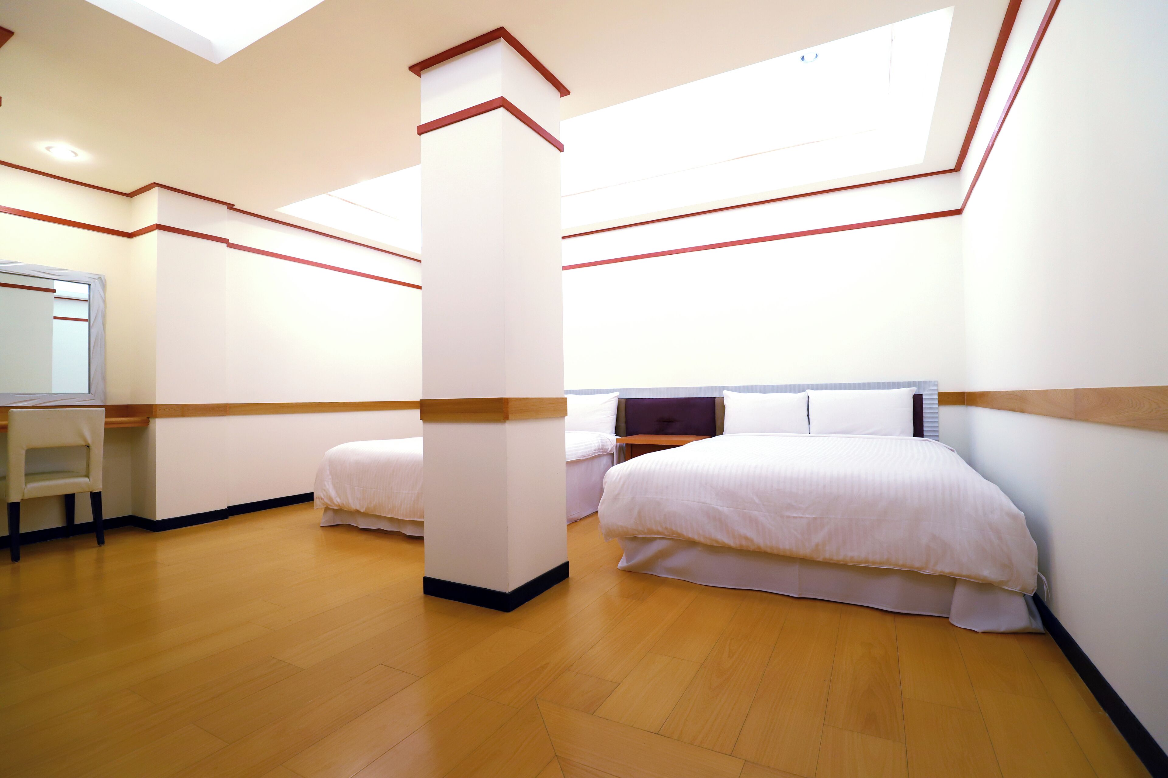 Ein Hotelzimmer mit zwei Betten, einem Schreibtisch und einem Spiegel.