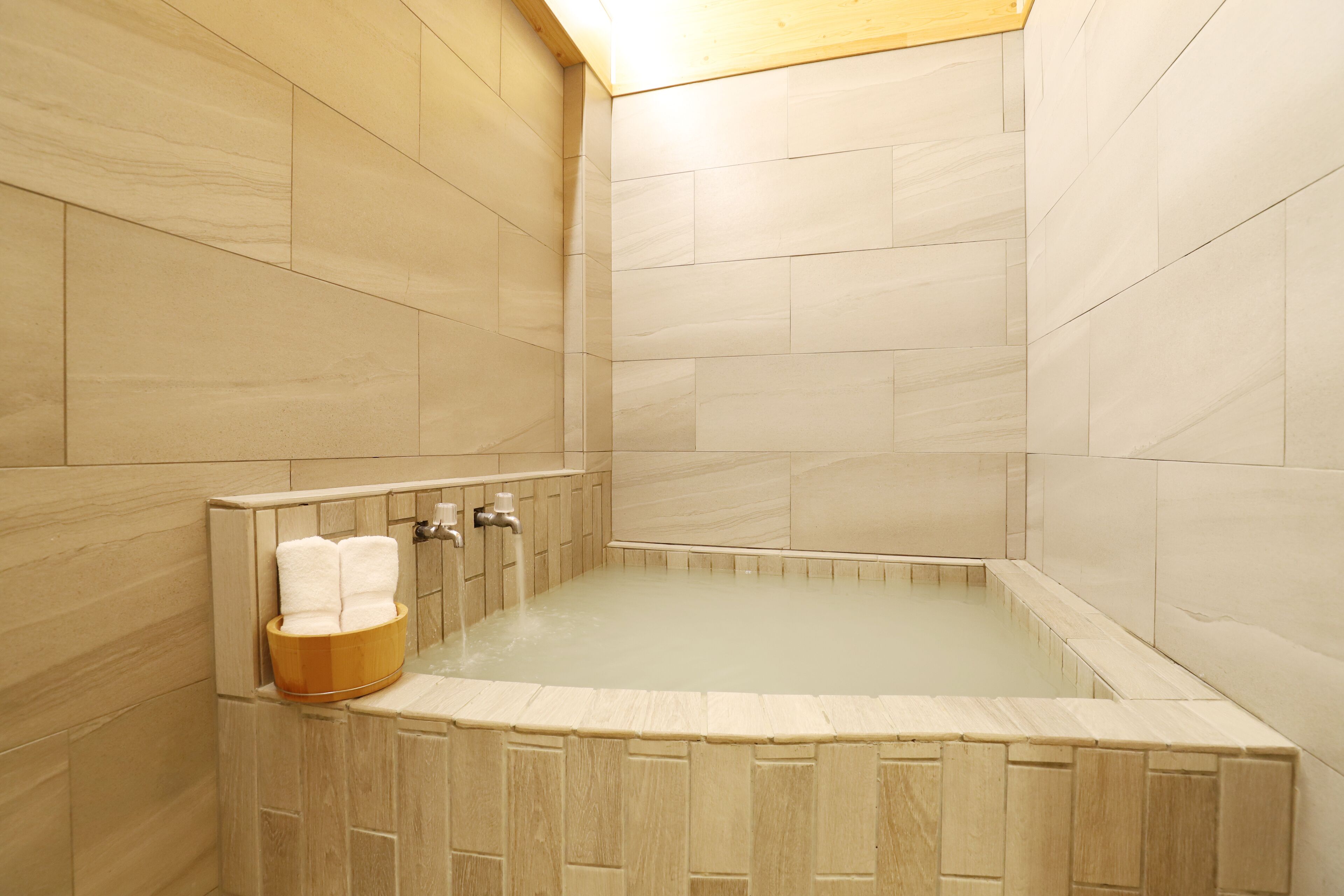 A modern bathroom with a freestanding bathtub, wooden bath mat, and a towel rack.