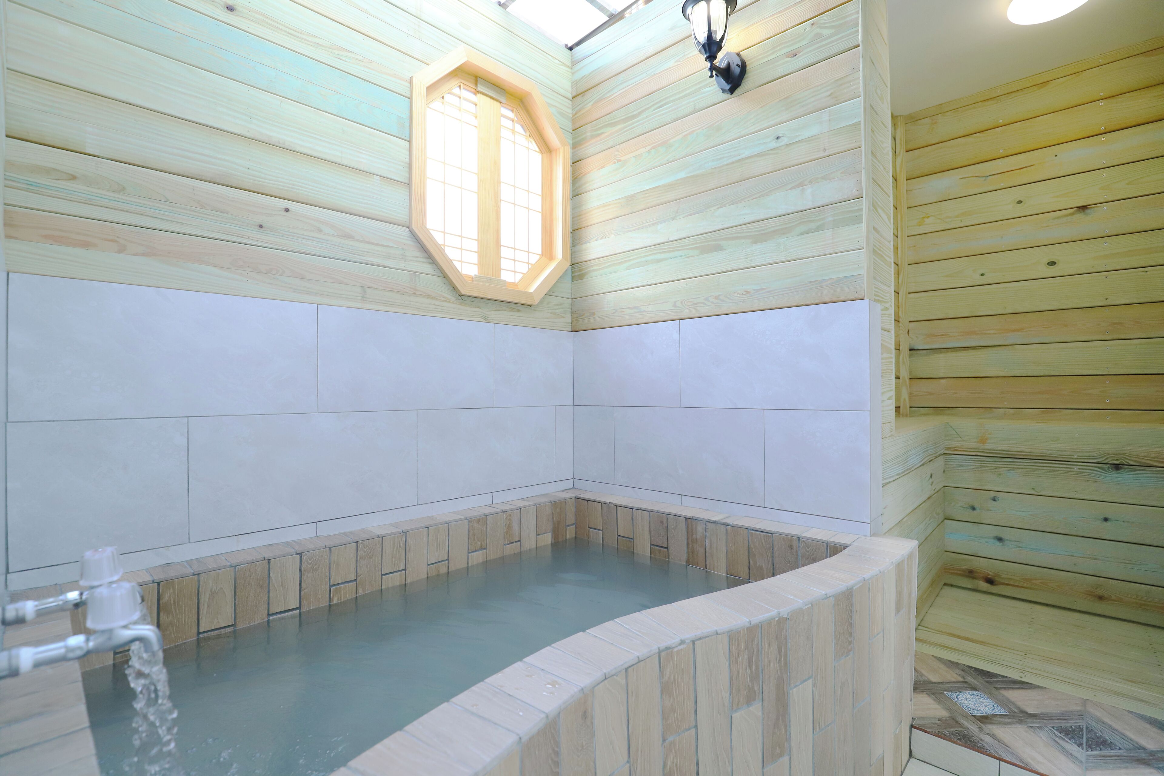 A wooden interior with a stone-tiled hot tub area.