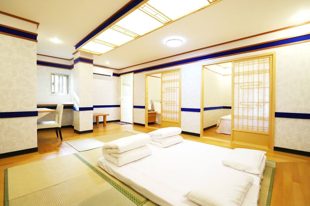 A hotel room with a bed, a desk, and a chair. There are towels on the bed and a window in the room.