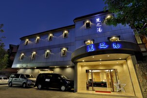 Un hotel con fachada moderna, varias ventanas y una entrada bien iluminada.