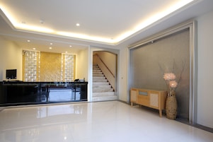 Un vestíbulo amplio con una mesa de recepción, una escalera y un jarrón decorativo.